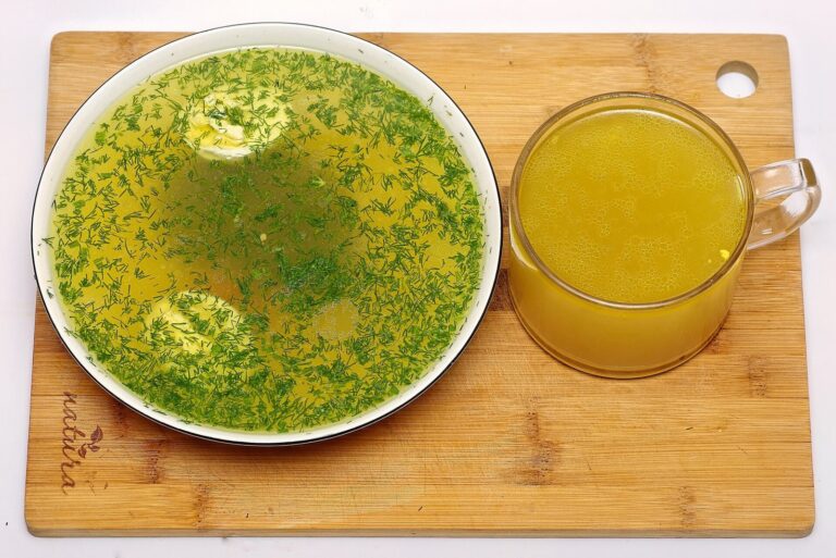 Klar hønsefond i en kop ved siden af en tallerken suppe