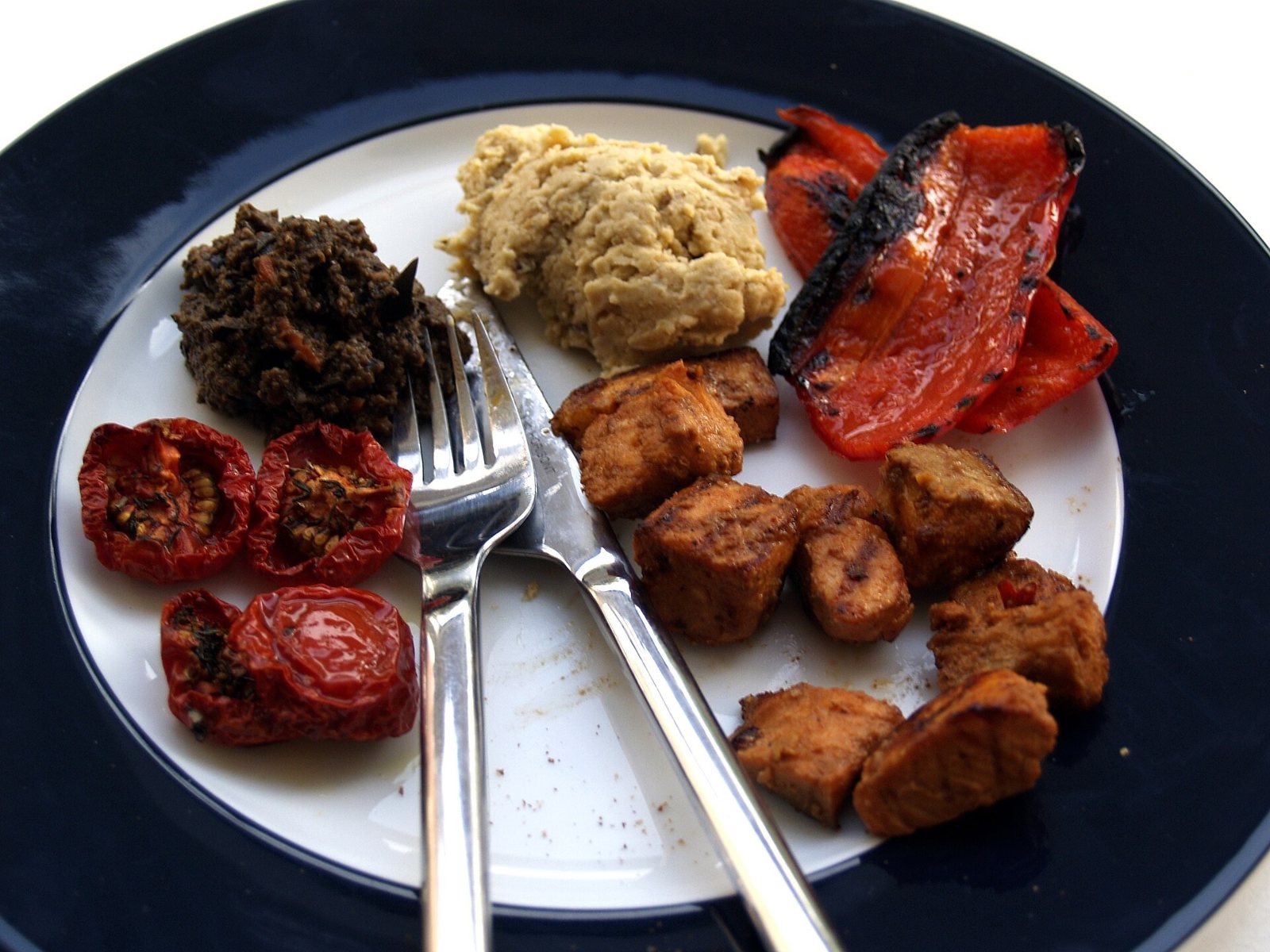 Semitørrede tomater serveret med hummus, tapenade og grillet peberfrugt